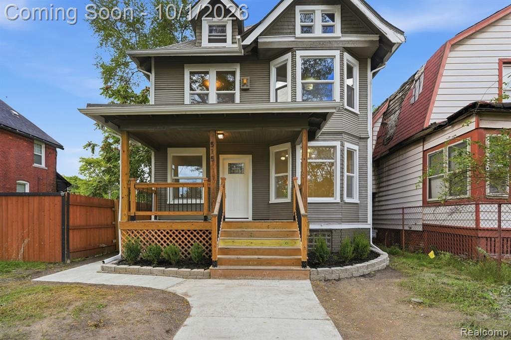 Inviting covered porch with wood railings and steps, featuring a white paneled entry door