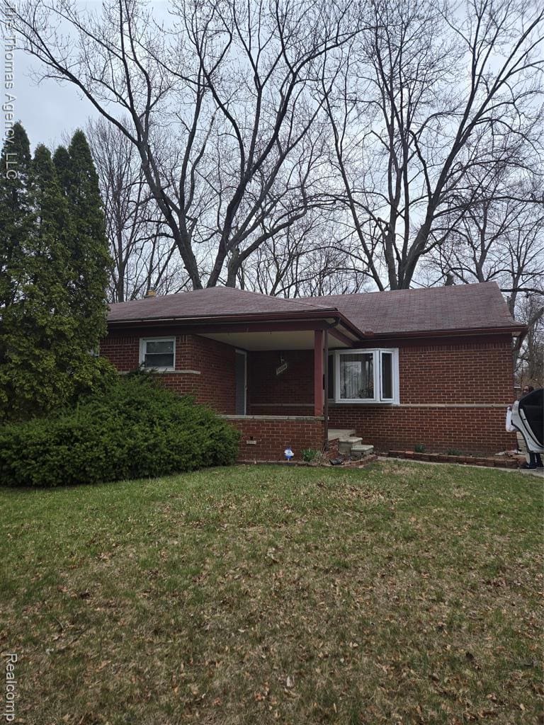 Ranch-style home featuring a front lawn, brick siding, and covered porch