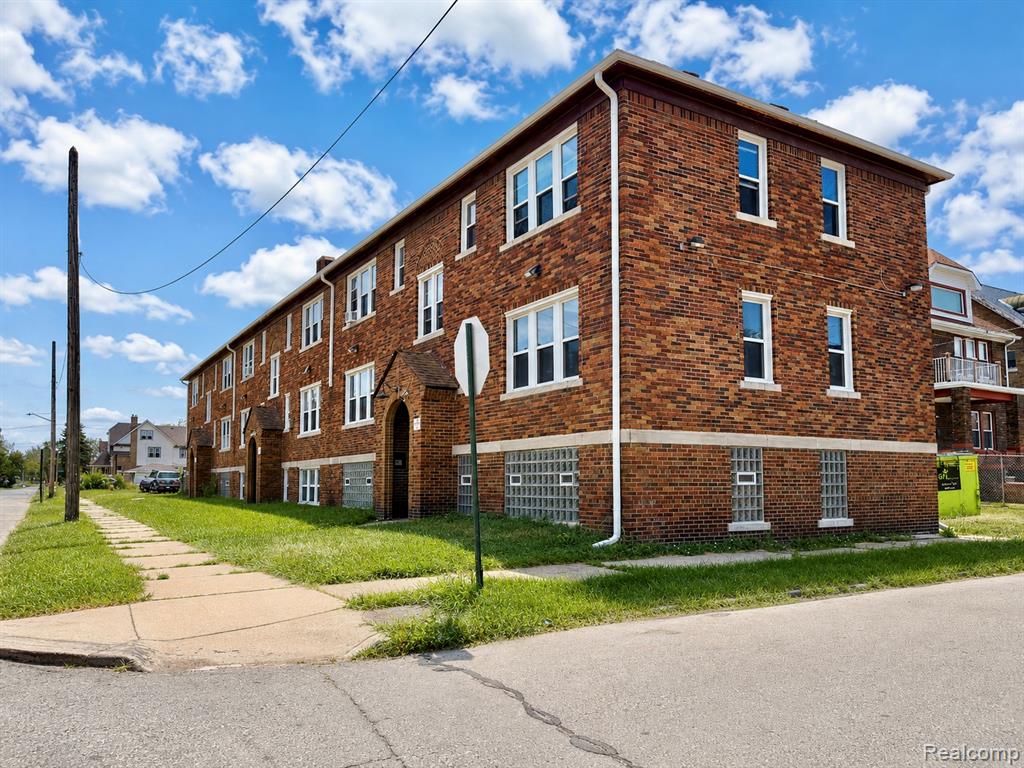 Brick apartment building featuring multiple windows, white window trim, and a prominent arched entryway