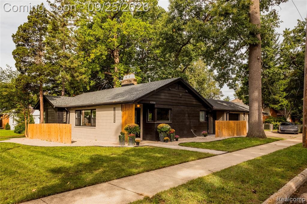 Exterior featuring light-colored siding, dark-colored siding, a gabled roof, and a wood accent wall