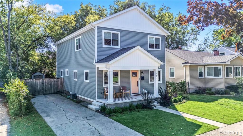 Two-story residence featuring blue horizontal siding, white trim, a covered front porch, and a paved driveway