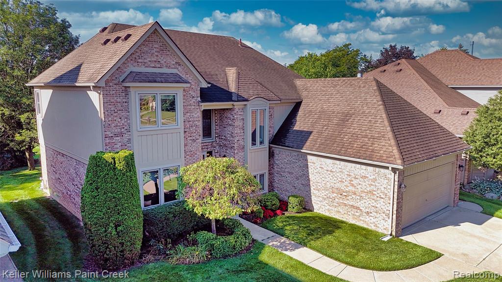 Brick exterior with tan siding accents, multiple gabled rooflines, an attached garage, and landscaped planting beds