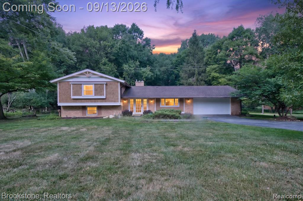 Brick and shake siding exterior with a pitched roof, attached two-car garage, and mature landscaping