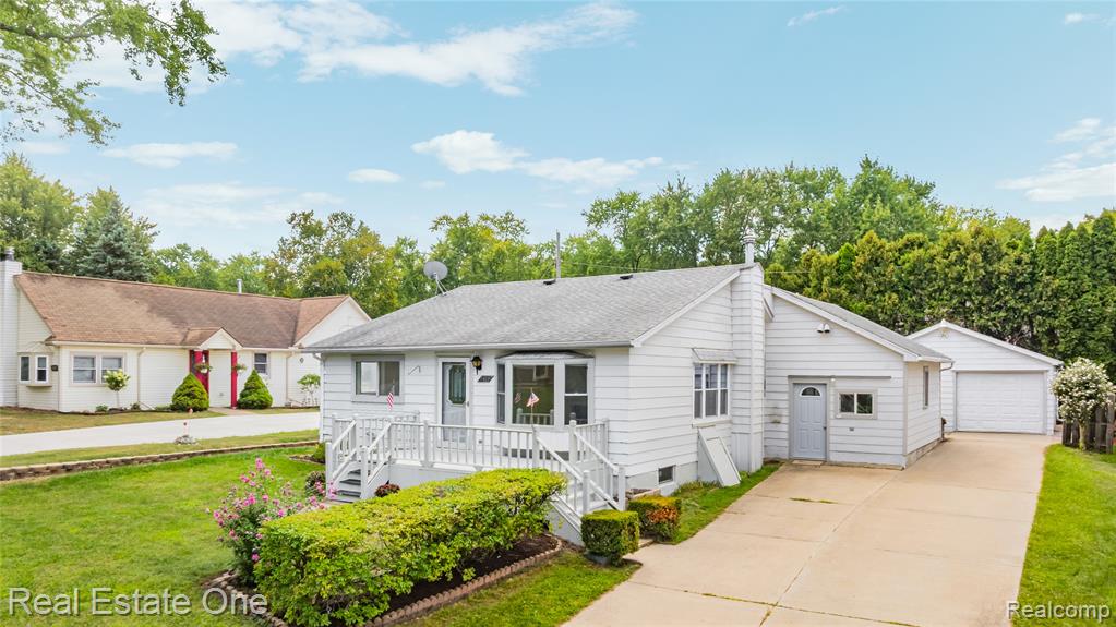 White exterior with gray trim, gray shingles, covered porch, bay window, and manicured landscaping