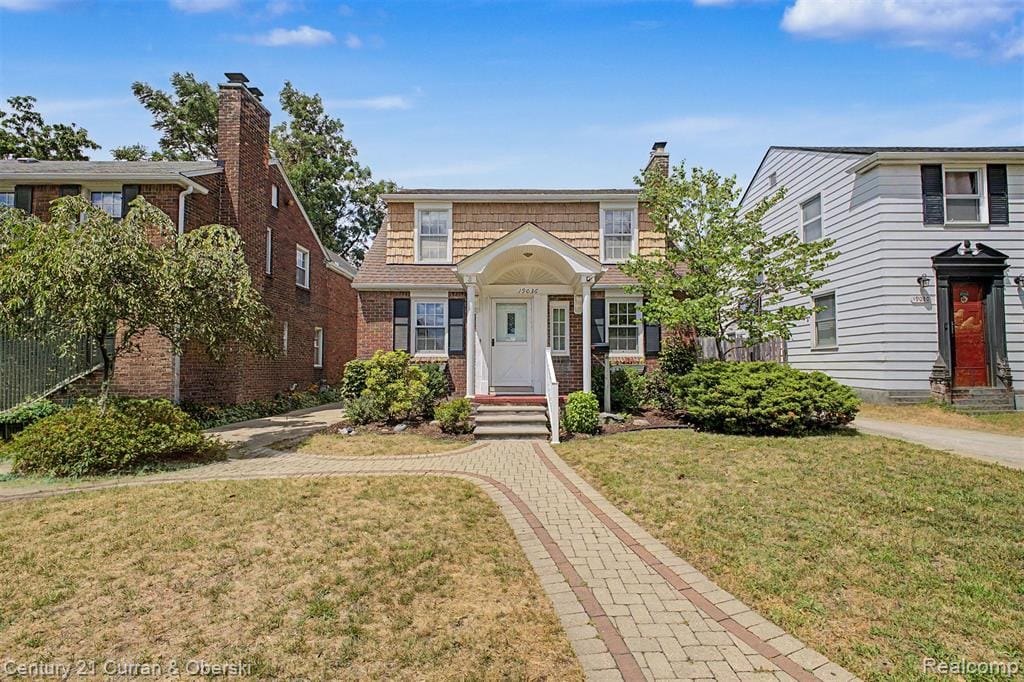 Traditional facade with dormer windows, brick and shake siding, and a covered entry