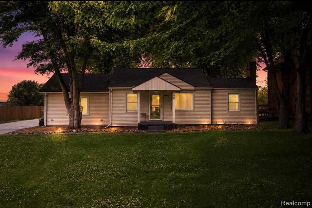 Siding exterior with a covered entry, dark shingle roof, and exterior accent lighting