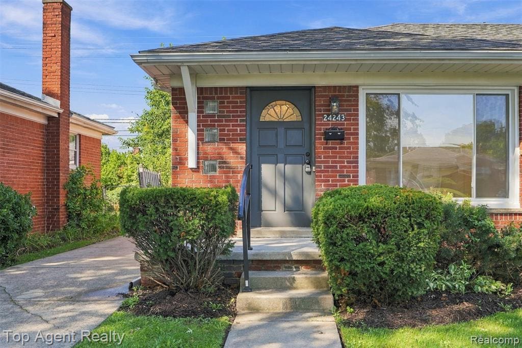 Brick exterior with a dark grey entry door featuring a decorative fanlight