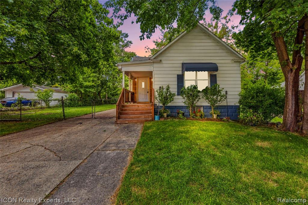 White siding exterior with a blue foundation, covered front porch, wooden steps, and a paved driveway