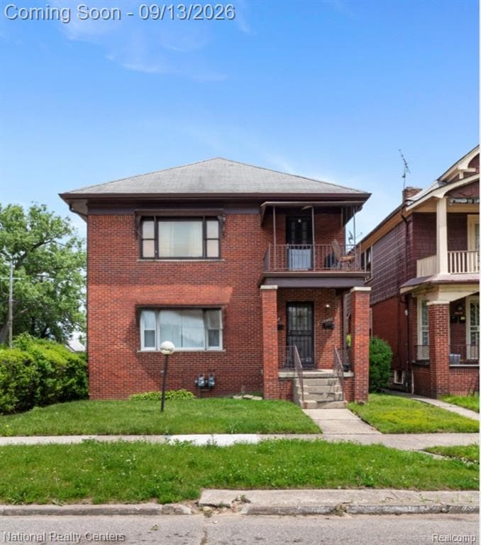 Brick-clad multi-story residence with a covered main entry and an upper-level balcony featuring metal railings