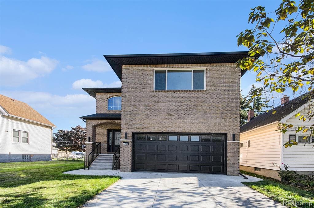 View of front facade featuring brick siding, a garage, concrete driveway, and a front lawn
