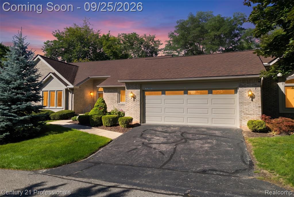 Brick exterior with a peaked roofline, attached garage, and a concrete pathway