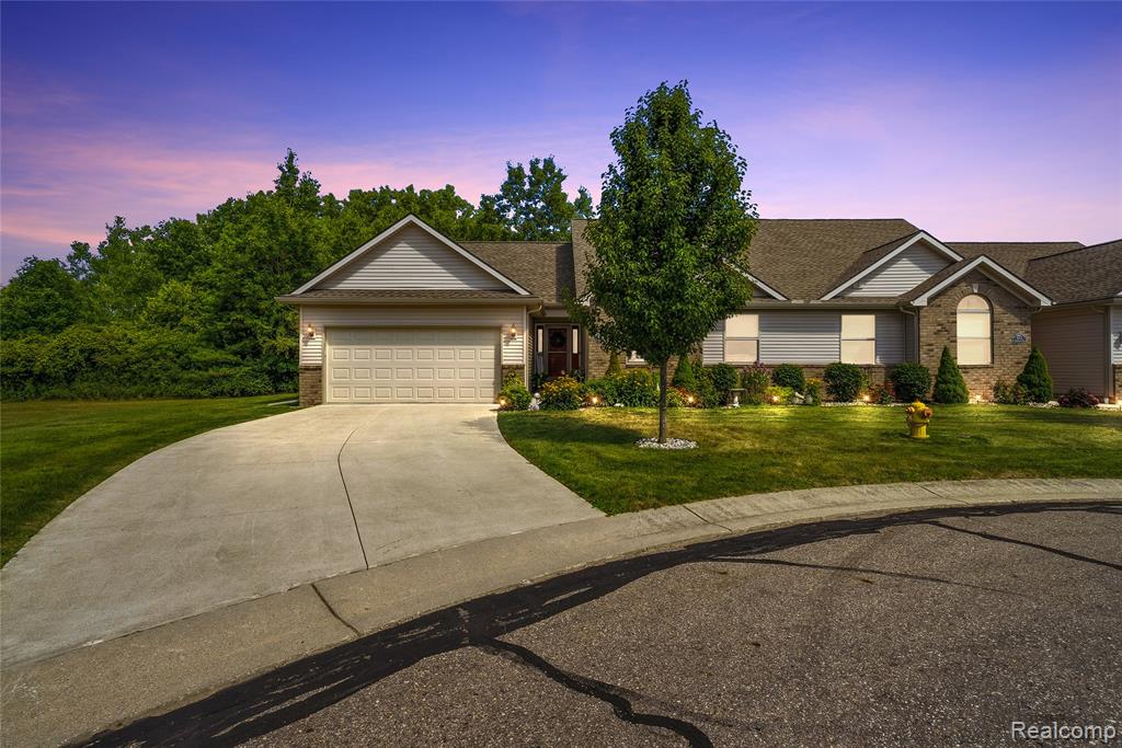 Ranch-style exterior with brick and siding accents, featuring a two-car garage, concrete driveway, and established landscaping with accent lighting