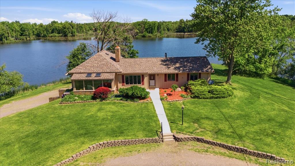A rare opportunity in Oakland County, this extraordinary estate spans more than 8 acres and occupies its own private peninsula on a 40 acre lake. With water surrounding the property on nearly every side, the setting is one that few will ever experience and even fewer will ever own. Perched atop a hill at the center of the peninsula, the ranch home captures panoramic water views from virtually every room and vantage point across the property. The home offers an open floor plan with expansive living spaces, abundant windows, and a finished walkout lower level leading to an inground pool overlooking the lake. A three car attached garage provides ample storage and convenience. Whether enjoyed as it stands today or reimagined to suit your vision, the setting alone is truly exceptional. The approach winds through mature woods before opening to a large circular drive and an impressive barn structure. Featuring multiple stalls and an expansive interior, the building has served a variety of purposes over the years, from equestrian use to equipment, RV, and recreational storage. Its scale and versatility create opportunities limited only by imagination. The lake is known for excellent fishing, while the surrounding landscape attracts abundant wildlife including deer and turkey. Properties of this caliber and setting rarely become available. For those seeking privacy, acreage, water frontage, and the chance to create a lasting legacy property, this is an opportunity not to be missed.