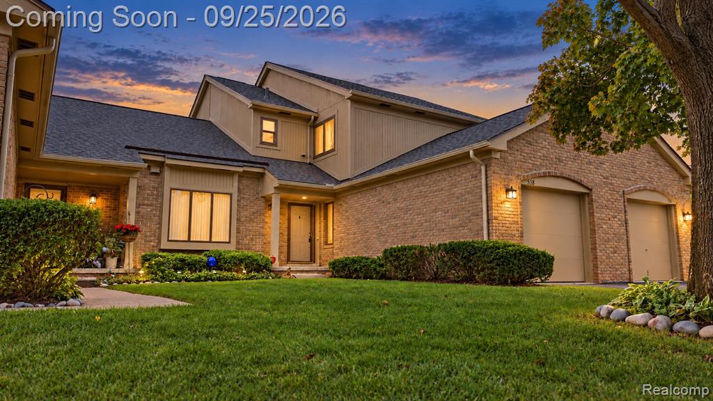 Brick and siding exterior with a dark shingle roof, two-car garage, and landscaped front yard