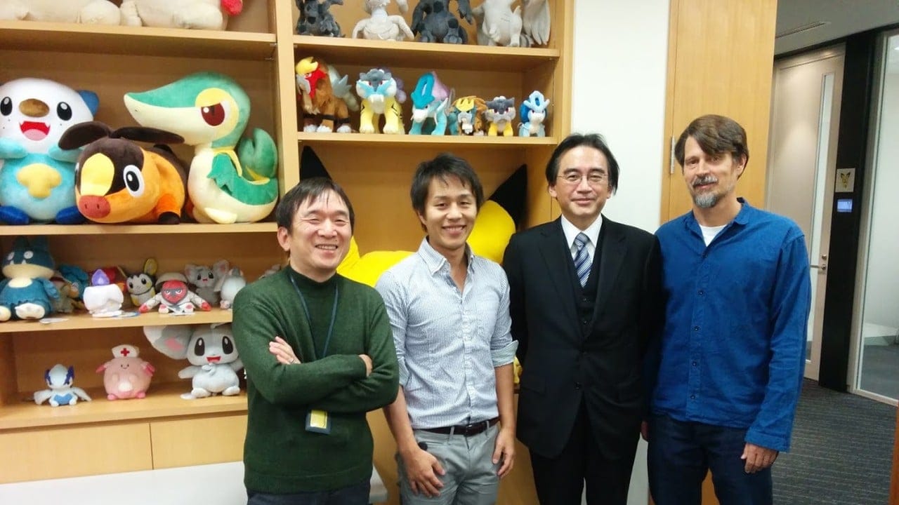 A group of four people standing in front of a cabinet filled with Pokémon plushies
