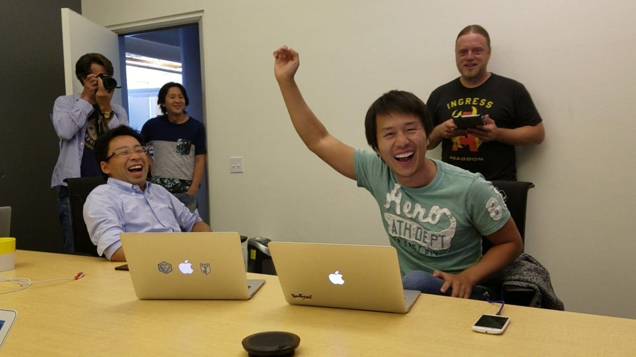 Tetsuo Nomura and the team smiling while launching the game from their Apple laptops