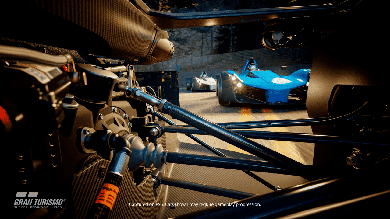 A close look inside of a car's engine while two other cars follow close behind.