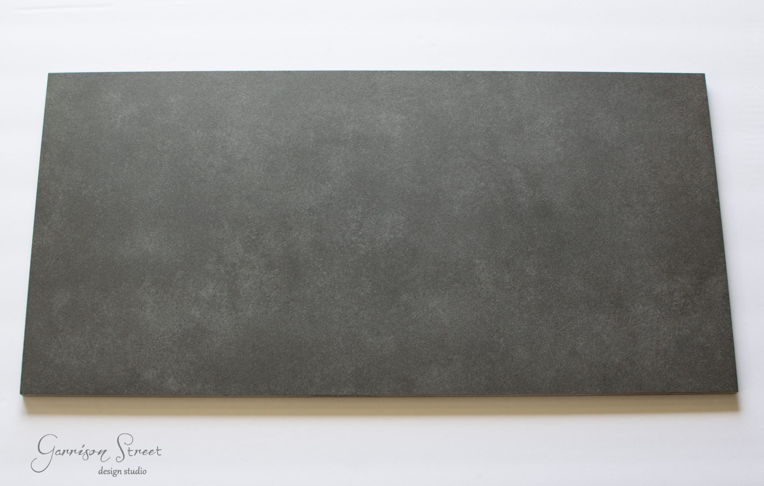 A large, rectangular, dark gray slate board with a subtle textured surface placed on a white background.