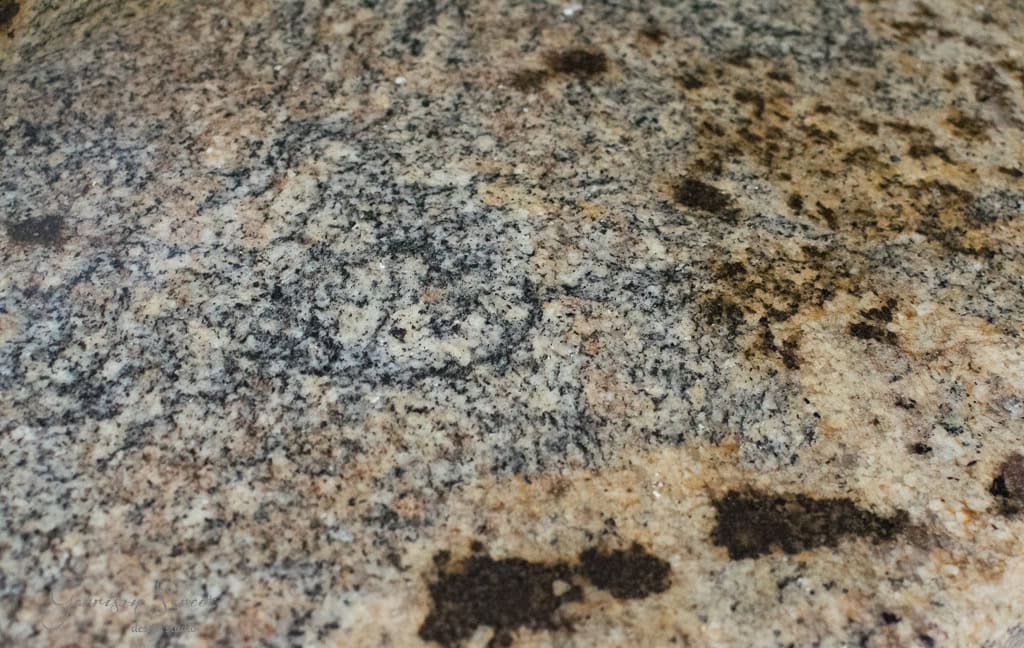 Close-up of a granite surface with a mixture of beige, black, and gray speckles creating a natural, textured pattern.