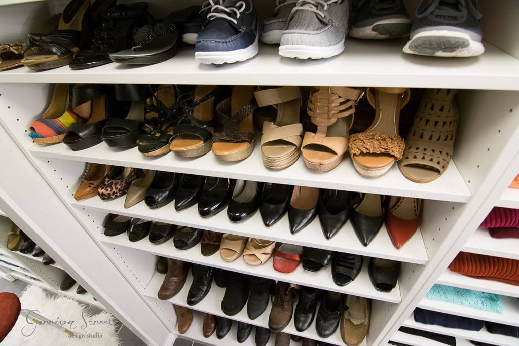 A neatly organized walk-in shoe closet reveals various styles. IKEA shelves display sneakers, high heels, wedges, and flats in different colors and materials. The well-lit space highlights every detail of the collection.