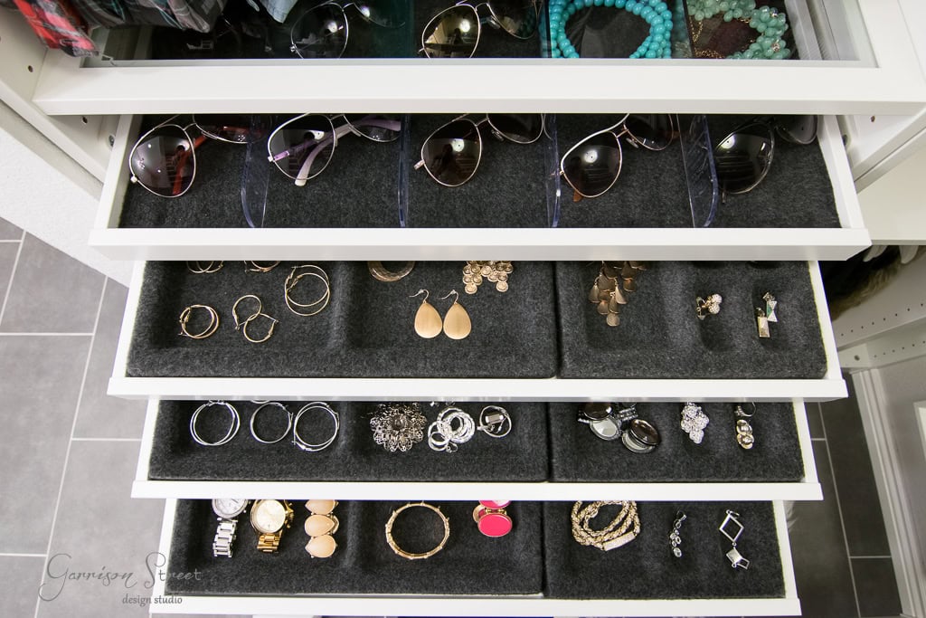 Open the closet drawer with organized accessories on black velvet. The top section holds sunglasses, while the middle sections display various earrings. In this IKEA-inspired setup, the bottom sections contain rings, bracelets, and watches, creating a visually appealing walk-in experience.