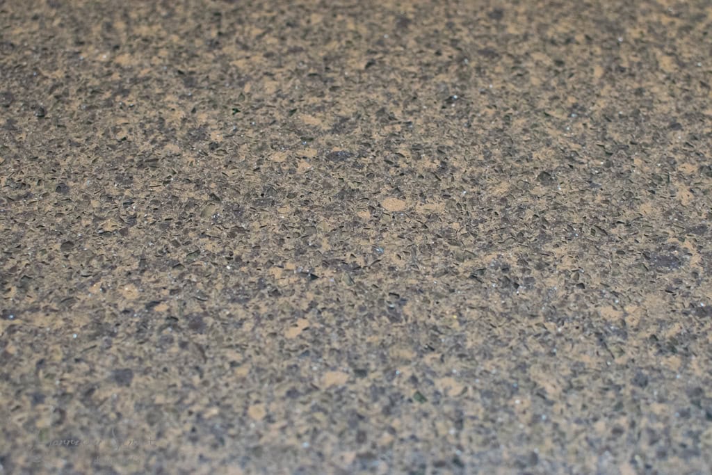 Close-up of a speckled, textured granite surface in shades of grey and beige, reminiscent of the refined look you'd achieve when learning how to make a kitchen island out of base cabinets. The surface features small, reflective mineral flecks that add a touch of elegance.