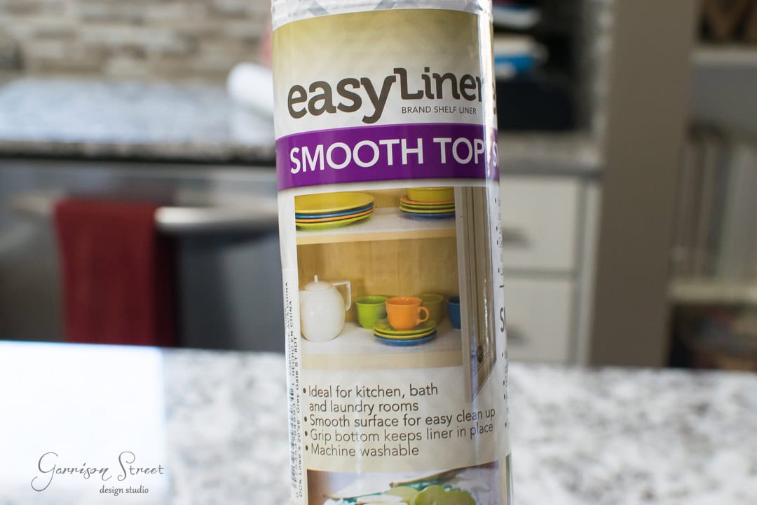 The packaging of an EasyLiner Smooth Top shelf liner roll showcases images of neatly organized shelves, complete with plates, cups, and bowls. Perfect for kitchens, baths, and even under the kitchen sink, it features a grip bottom and is machine washable for effortless organization.