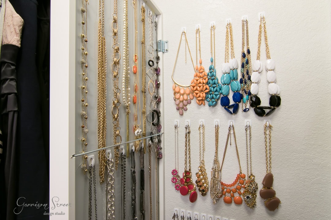 An IKEA wall jewelry organizer elegantly displays gold and silver necklaces, bracelets, and colorful statement pieces in blue, pink, orange, and black. Complete with hooks and rods for neat hanging, it even includes a mirror to help you perfect your look.