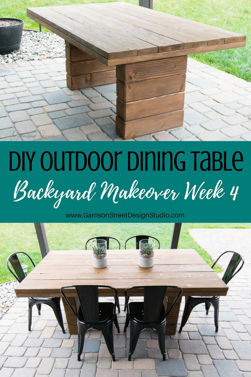 A wooden outdoor dining table with a modern design features sturdy block legs. It is styled with black metal chairs and three small potted plants on top. The image includes text: "DIY Outdoor Dining Table, Backyard Makeover Week 4".
