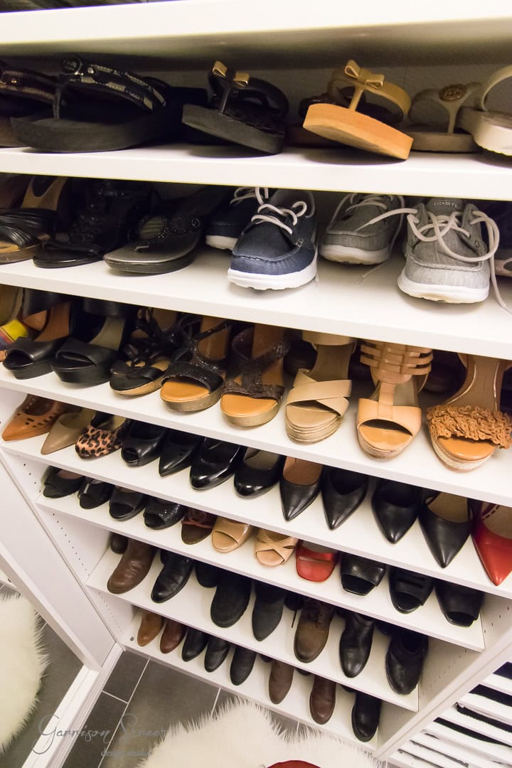 A neatly organized shoe closet design features six shelves displaying a variety of footwear, including athletic shoes, sandals, flats, and heels. The shoes are arranged by type and color, creating a clean and tidy appearance.
