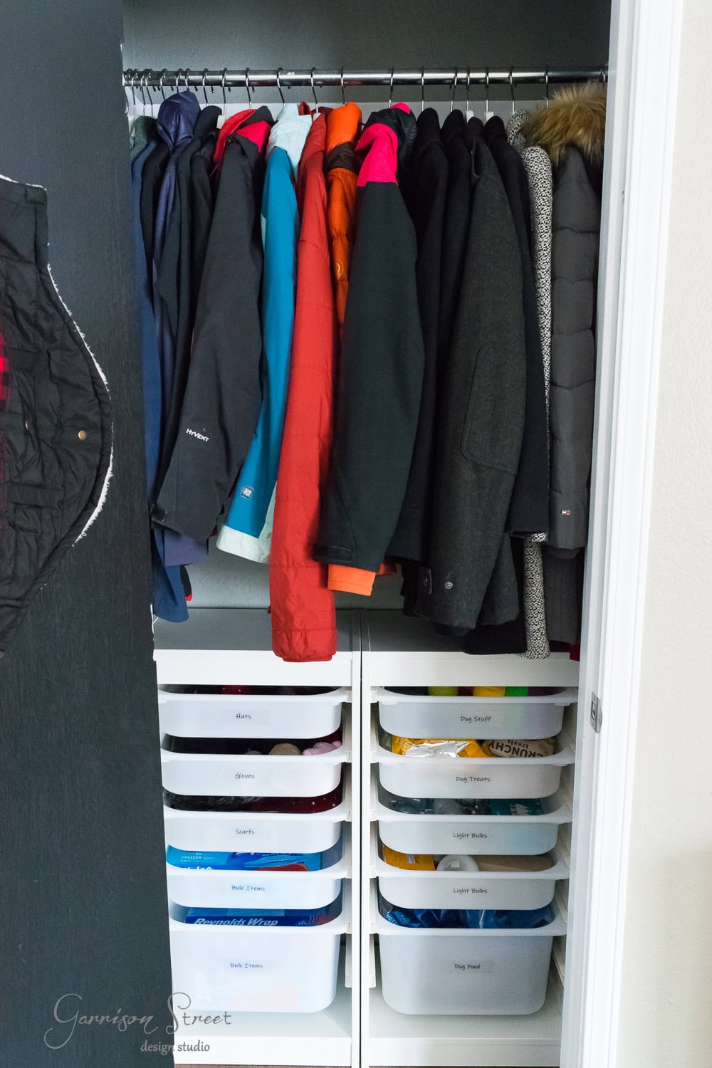 A neatly organized closet boasts IKEA's efficient design, with winter coats hanging above stacked plastic drawers. The drawers, labeled with categories like "Gloves," "Hats," and "Socks," create a tidy and efficient space for seamless organization.