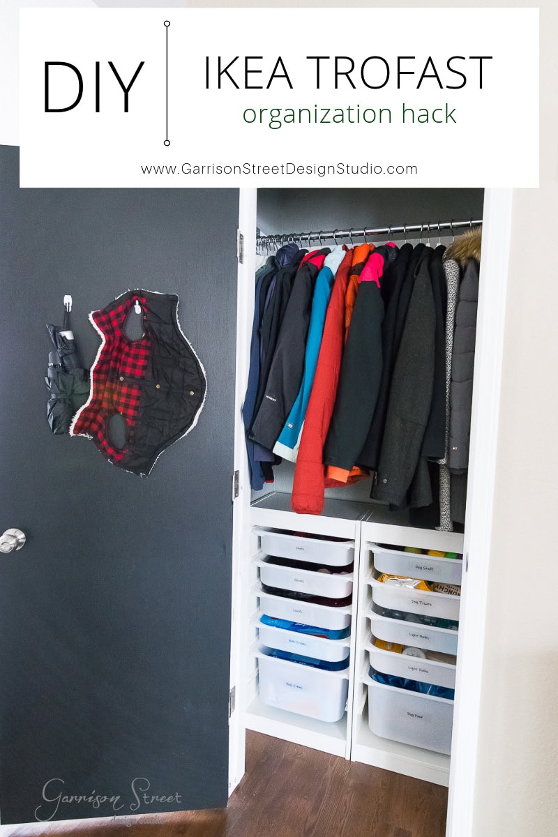 A closet efficiently uses IKEA TROFAST bins for flawless organization. Clothes hang neatly above, while jackets find a cozy home inside. A DIY sign proudly declares the "IKEA TROFAST closet hack" from Garrison Street Design Studio.