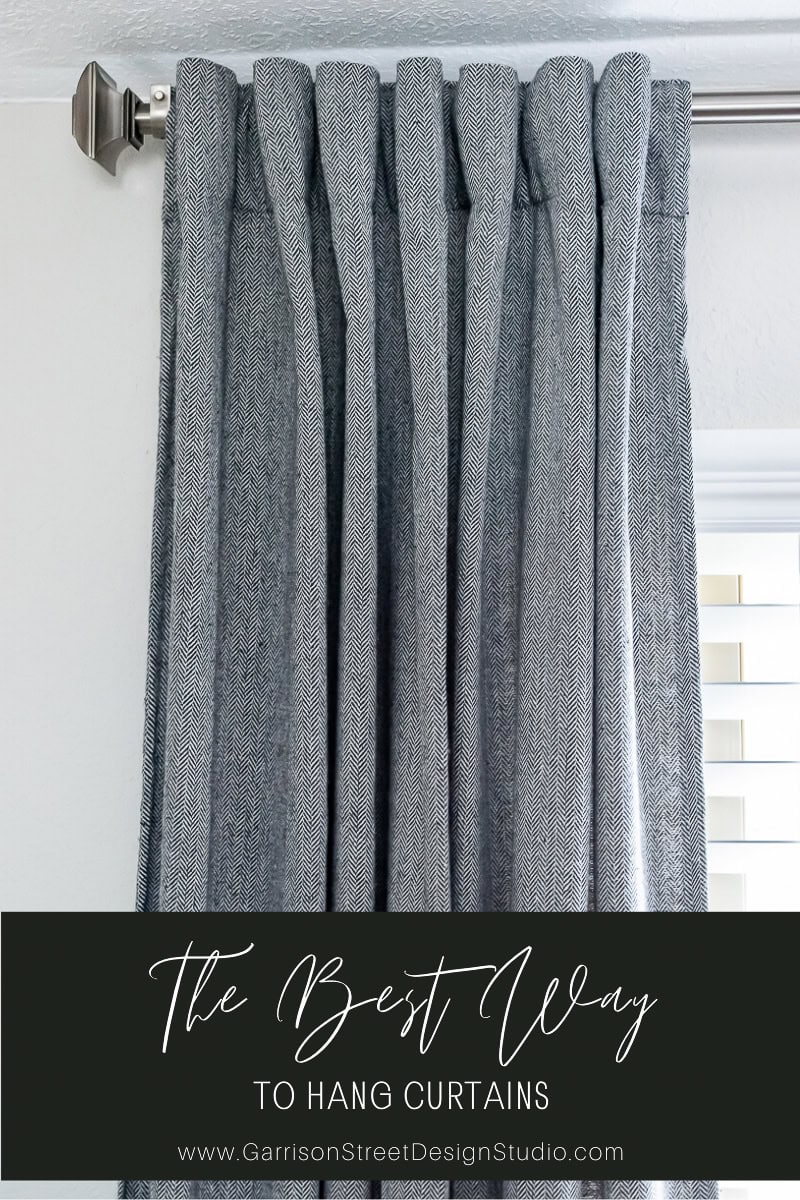 A close-up of elegant gray curtains hanging perfectly from a sleek silver rod. The text at the bottom reads "Discover the Best Way to Hang Curtains" followed by "www.GarrisonStreetDesignStudio.com".
