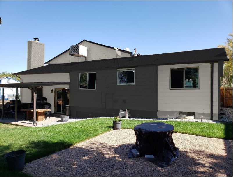 A modern two-story house with a patio and lush grassy backyard features a black chimney on the left. Potted plants are scattered throughout, enhancing the charm. A covered round table graces the foreground, inviting relaxation amidst this elegant blend of brick and nature.