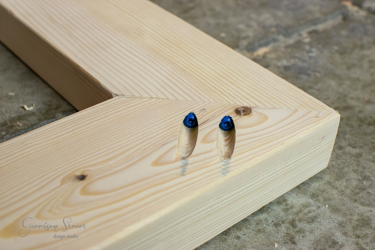 Close-up of two wooden planks joined together using pocket screws. The light-colored wood contrasts beautifully against the concrete surface, with the screws partially visible within the material.