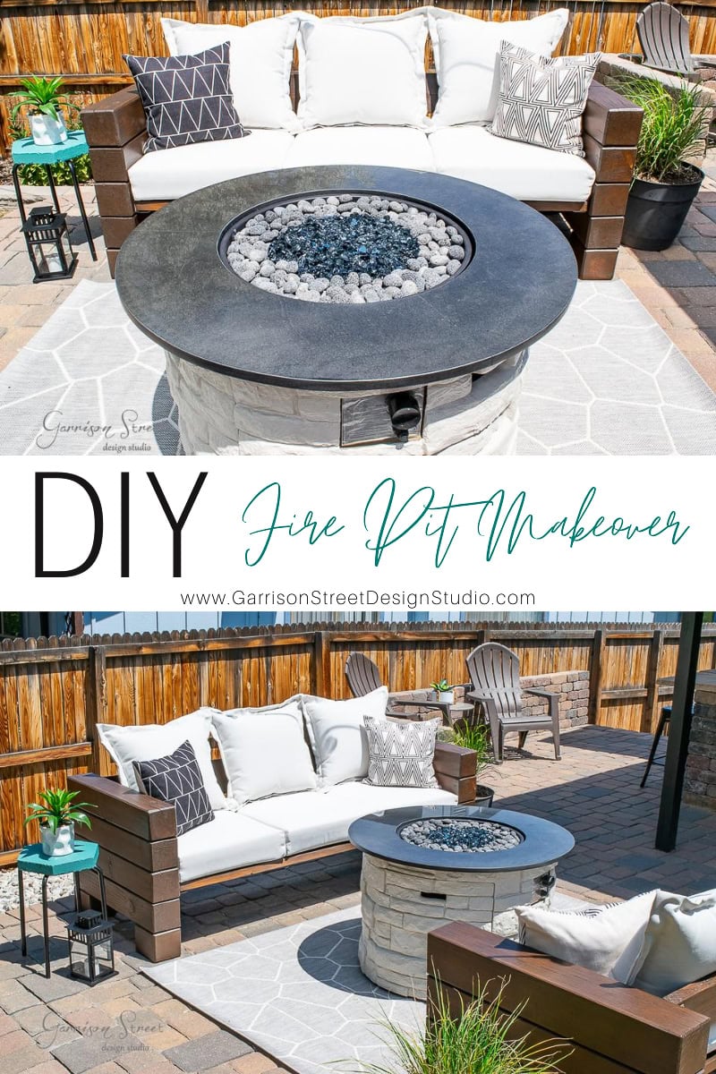 Outdoor patio scene with a round fire pit brimming with gray rocks. The area features a cozy white sofa adorned with patterned pillows, side tables, and a wooden privacy fence.