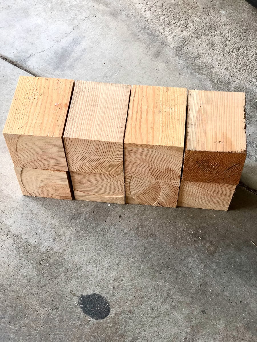 Six wooden blocks arranged in two rows of three on a concrete surface, reminiscent of an outdoor sofa's rustic charm, showcasing various wood grain patterns and light to darker hues.