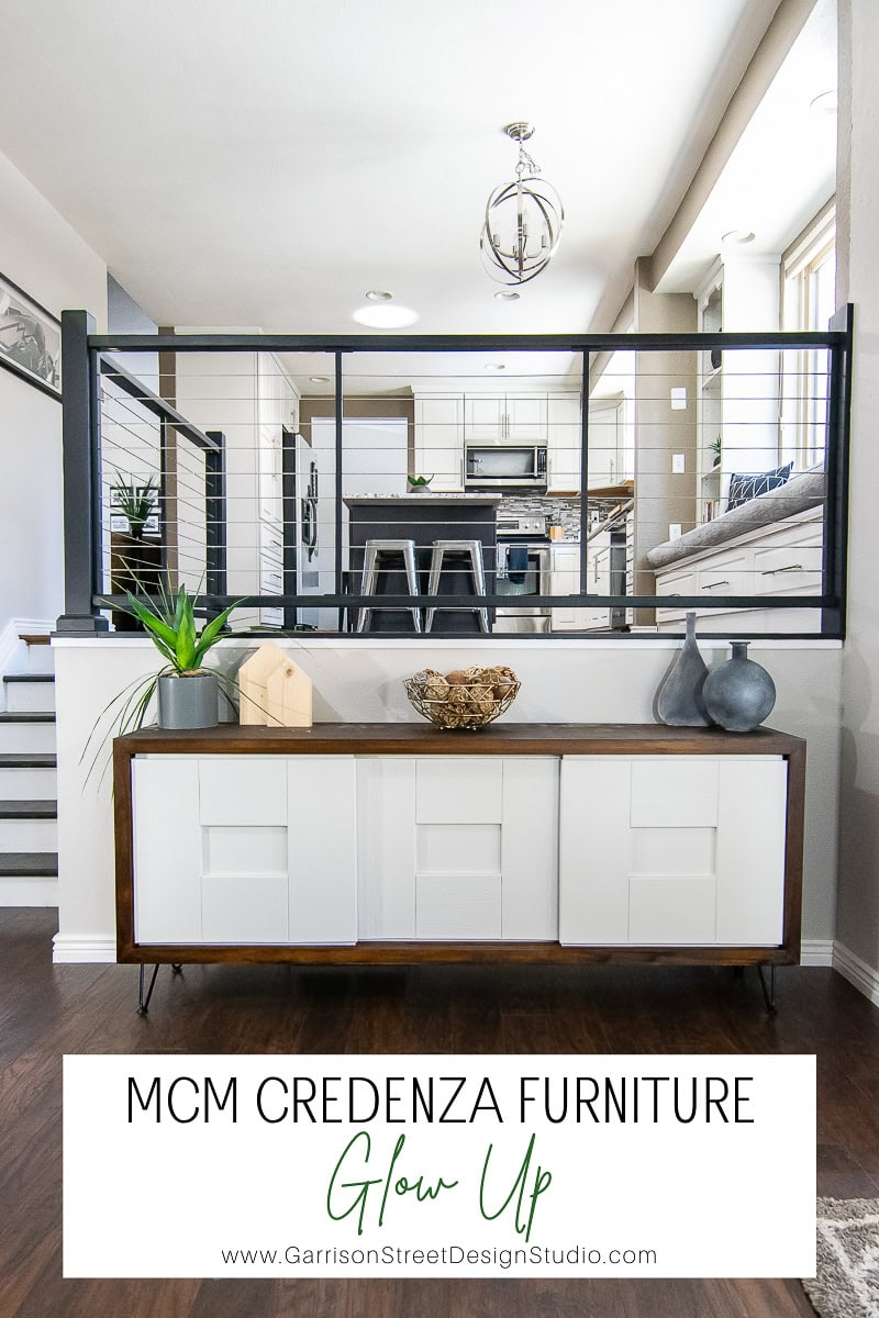 A modern living space showcases a stunning MCM credenza with a white facade and wooden accents. Decorative vases adorn it, enhancing the furniture's glow up. In the background, an open-plan kitchen and living area bask in natural light. Text reads: "MCM Credenza Furniture Glow Up.