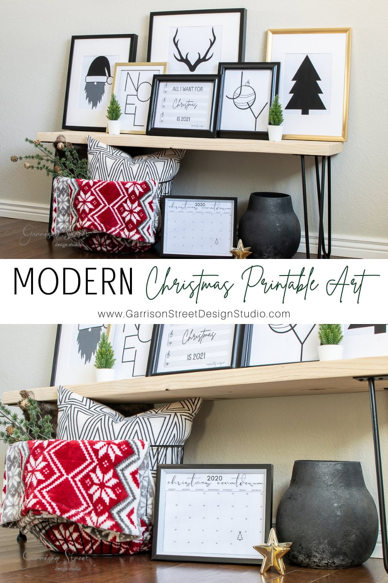 Cozy holiday-themed decor featuring printable framed art, pillows, and a calendar displayed on wooden shelves. Includes a minimalist Christmas tree, deer, and Noel designs. Black vases and a red patterned pillow add festive accents to this charming Christmas display.