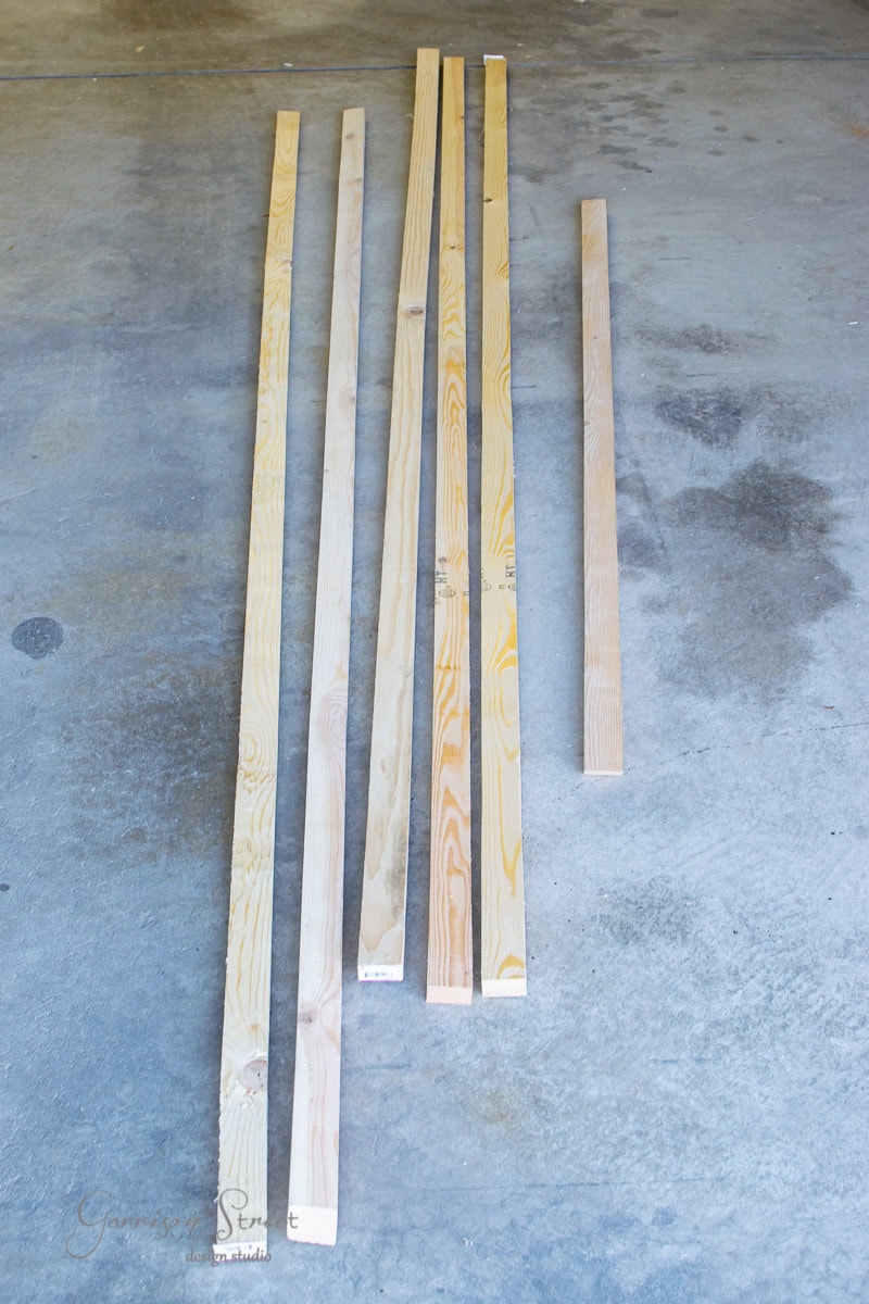Five long wooden planks of varying widths lay out on the concrete floor, a perfect start for crafting a rustic floating shelf or perhaps refurbishing an old bar to add a touch of charm. Despite the damp air, their beauty remains unaffected.