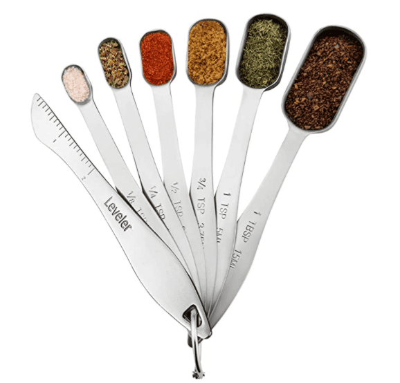 A set of six stainless steel measuring spoons, perfect for your spice cabinet organization, is fanned out on a ring. Filled with various spices, these spoons have engraved measurements and include a leveling tool on the side.
