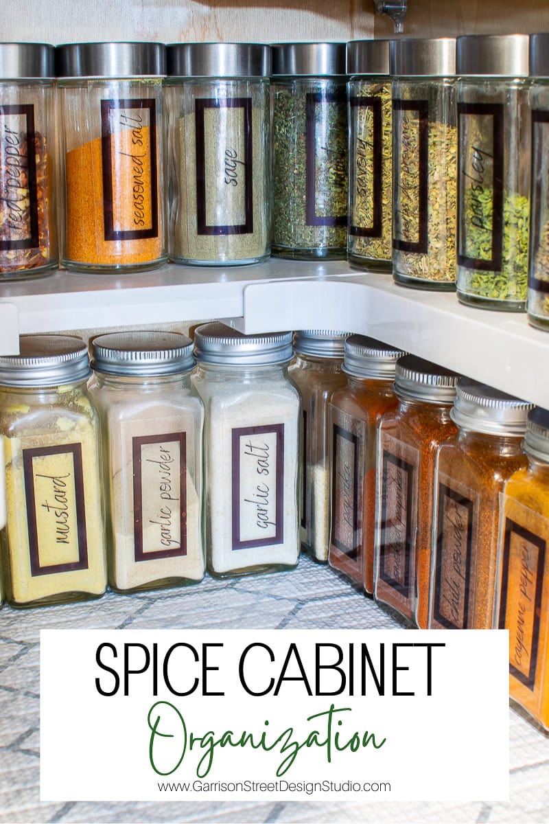 A neatly organized spice cabinet showcases labeled jars filled with spices like mustard and garlic salt, all arranged in tidy rows on white shelves. The organization reflects the precision of a design studio, whose logo is subtly visible at the bottom.