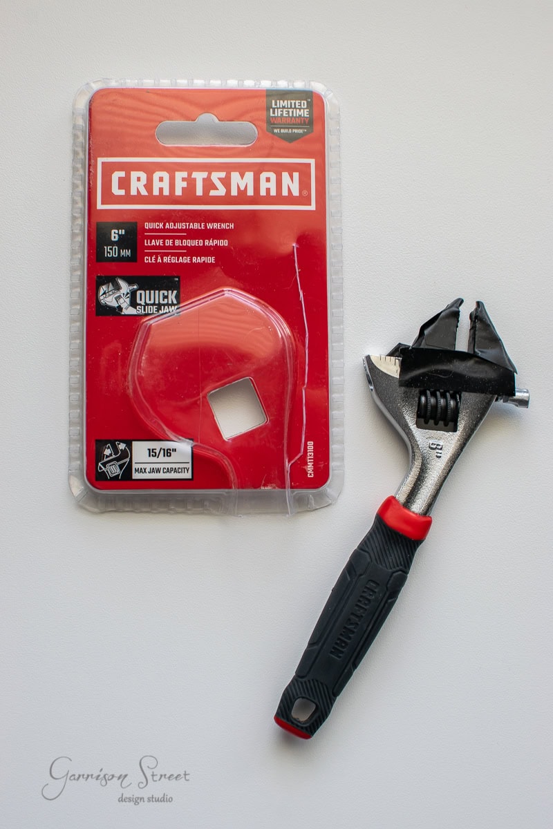 The packaging features a 6-inch Craftsman adjustable wrench with a sleek black and red handle, perfect for any DIY enthusiast. Labeled "Quick Adjustable Wrench," it boasts a max jaw capacity of 15/16". It's ideal for projects like cable railing installations. The wrench is partially removed from its packaging.
