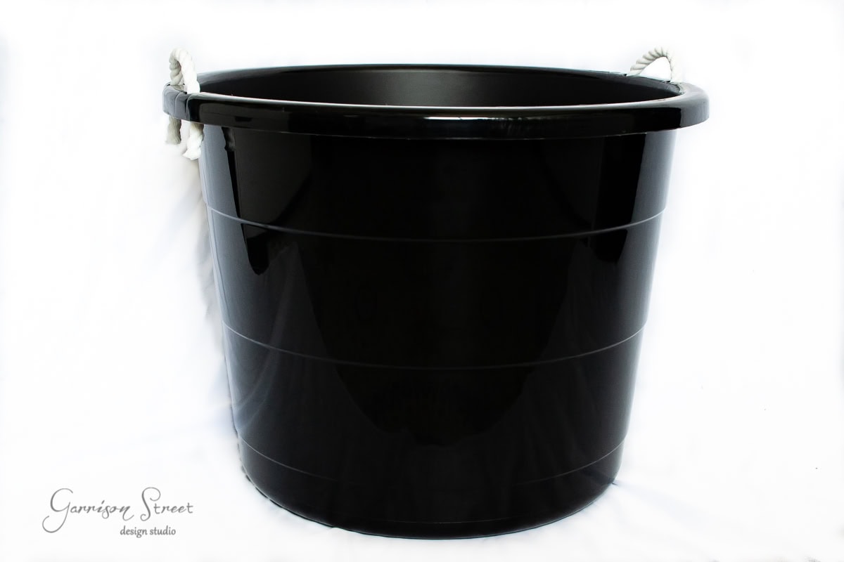 A large, black plastic bucket with two white rope handles on either side, set against a plain white background, perfect for DIY enthusiasts looking to create a unique planter.