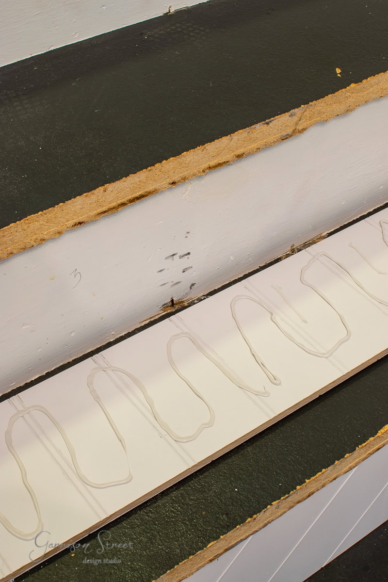 Cross-sectional view of a sandwich panel with layers including a green top, a beige core, and a white bottom. Visible adhesive lines on the white layer detail its construction, reminiscent of stair treads in precise alignment.