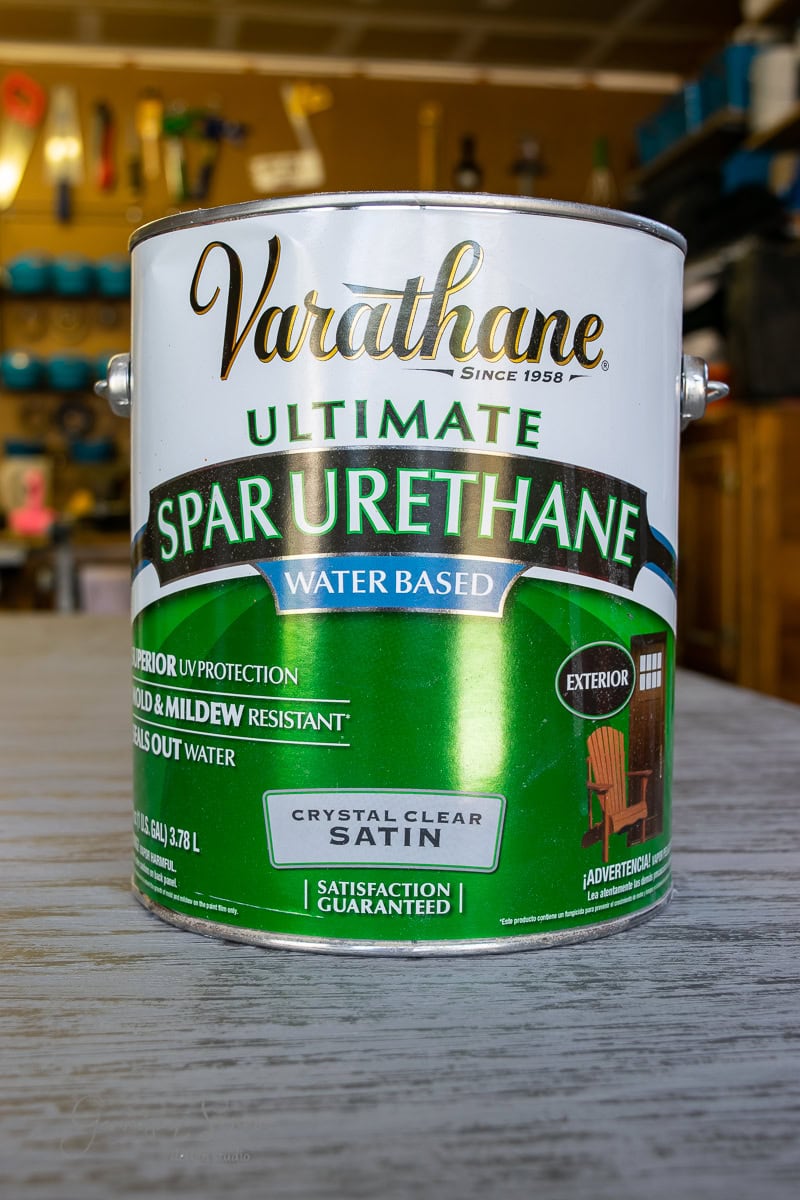 A can of Varathane Ultimate Spar Urethane, water-based, sits on a wooden surface. Perfect for exterior use, it offers UV protection and mold resistance with a crystal-clear satin finish. The label highlights satisfaction guarantee.