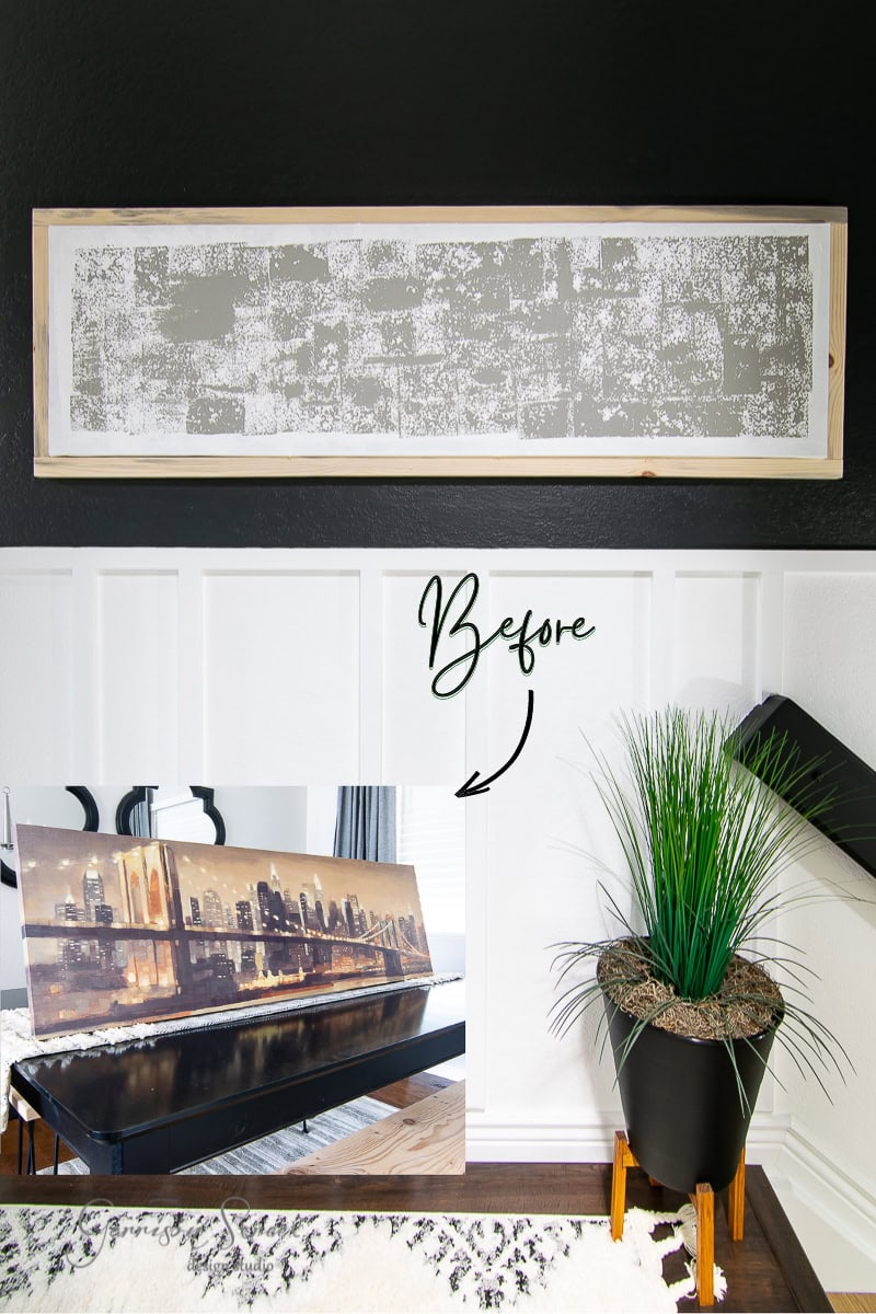 A room features framed canvas art depicting a black wall design and a photo of a cityscape painting before it was painted over. A plant in a black pot sits beside the wall, while part of a black and white rug graces the dark wooden floor.