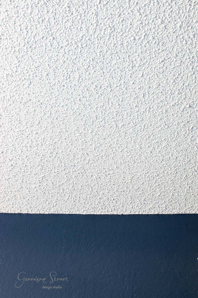 Close-up of a wall in a modern boho style, featuring textured white paint on the upper section and smooth dark blue paint on the lower section, reminiscent of a chic bunk room design.