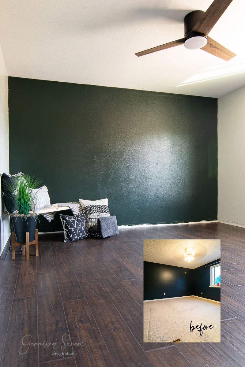 A room with dark green walls and elegant laminate wood flooring. A ceiling fan is visible. There's a bench with pillows and a plant on the left. An inset image shows the "before" state with carpeted flooring and a different light fixture.