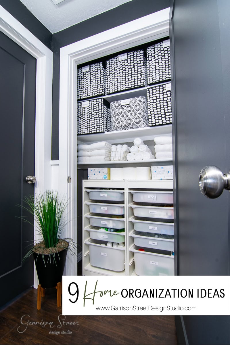 A neatly organized closet with black and white baskets, stacks of towels, and labeled drawers showcases impeccable organization. A small plant in a black pot rests on the floor nearby. Text reads "9 Home Organization Ideas" with a website URL.